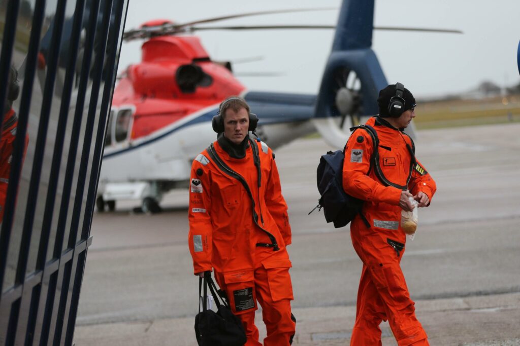Offshore personeel en helicopter op weg naar offshore eiland vanaf Den Helder Airport