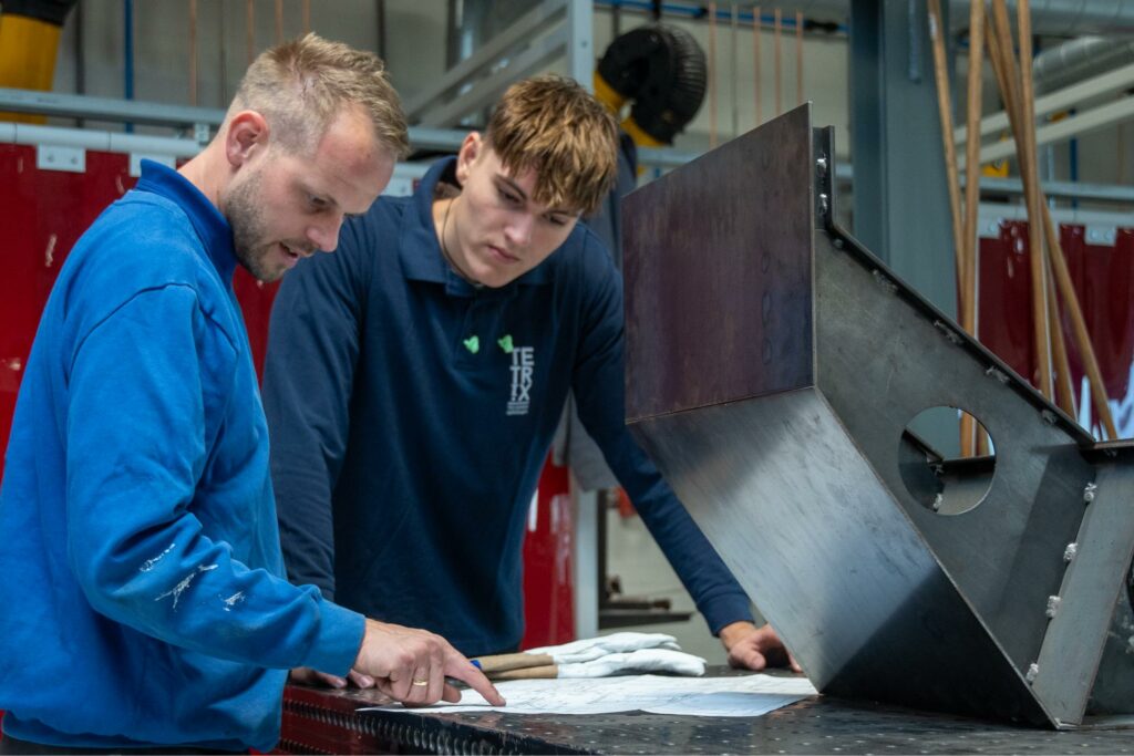 Leerling en docent bekijken tekening van las