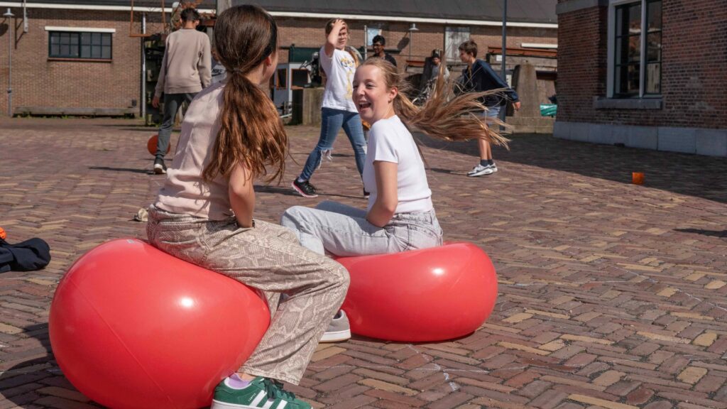 Kinderen op een skippybal op Willemsoord nabij de scheepshelling