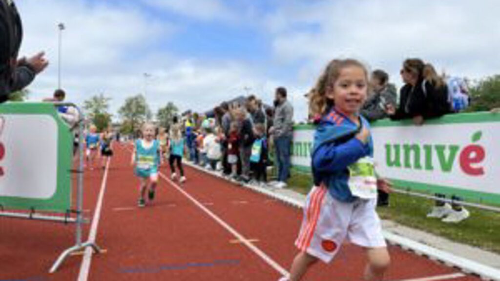 Kinderen lopen op de atletiekbaan voor de scholierenveldloop