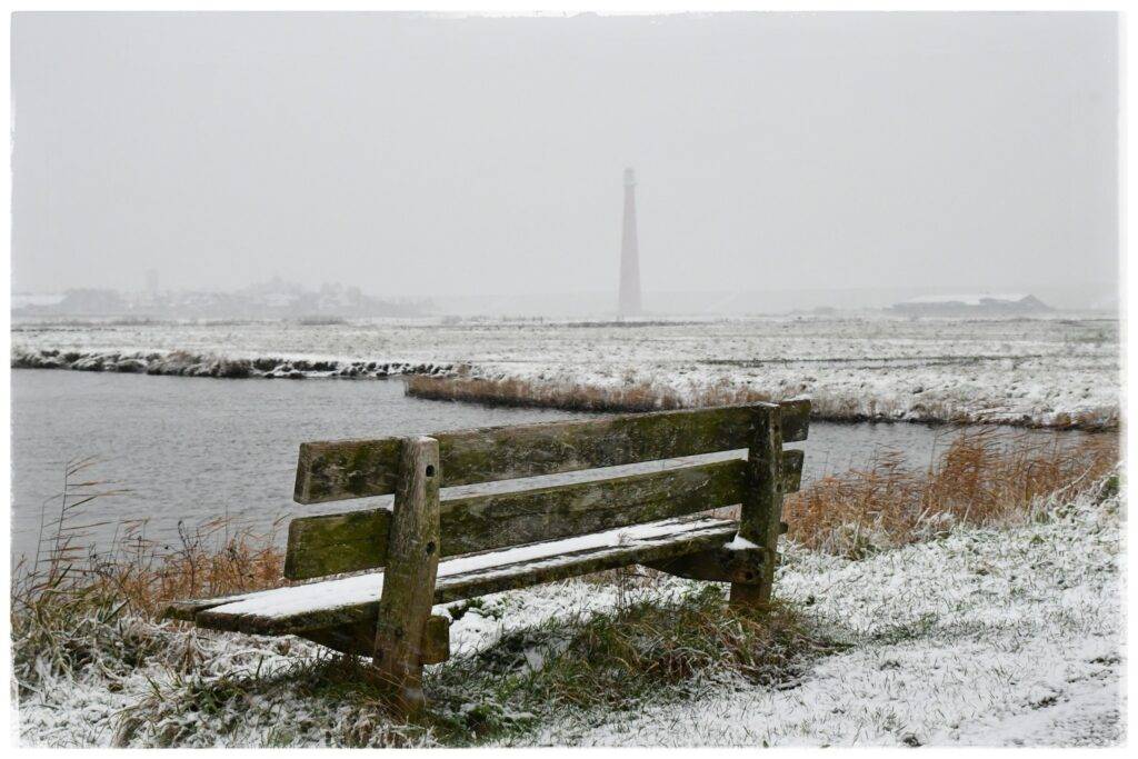Mooiste Helderse plaatjes met bankje in de sneeuw met de Lange Jaap op de achtergrond
