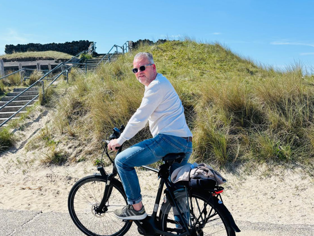 Ambassadeur Peter Dunselman op de fiets langs de zandsculpturen